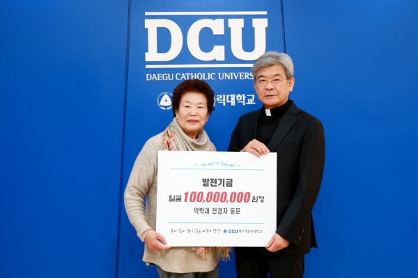 전경자 동문(왼쪽)이 김정우 총장에게 발전기금을 전달하고 있다.