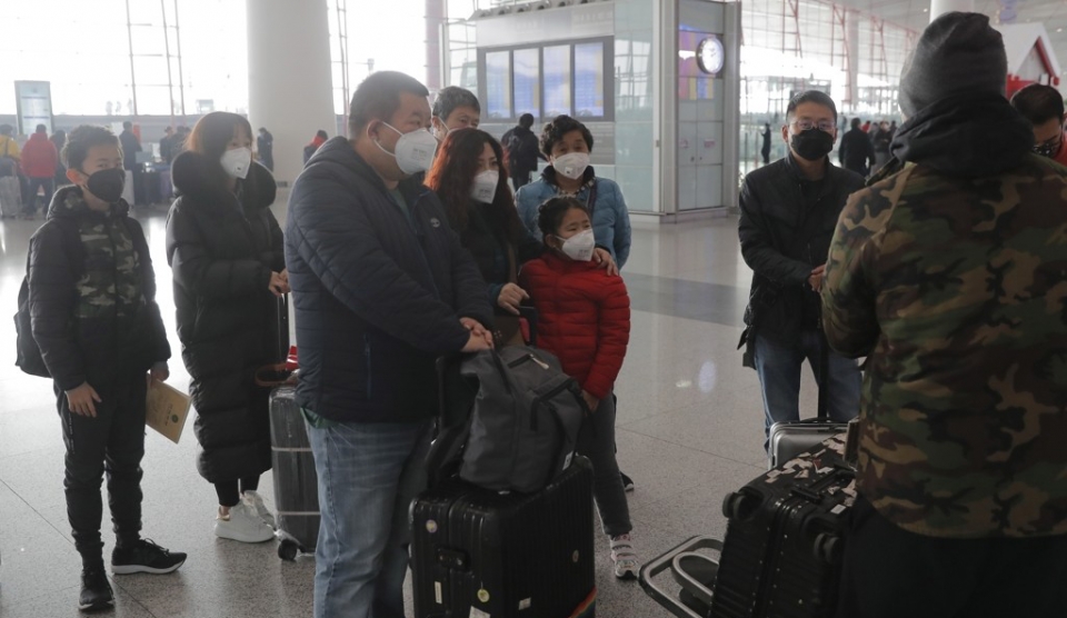 마스크를 착용한 단체 관광객들이 26일 베이징의 서우두 국제공항의 제3터미널에서 가이드를 바라보고 있다. 중국 정부는 이날 여행사들에 국내외 단체 관광 상품의 판매를 중단토록 지시했다.