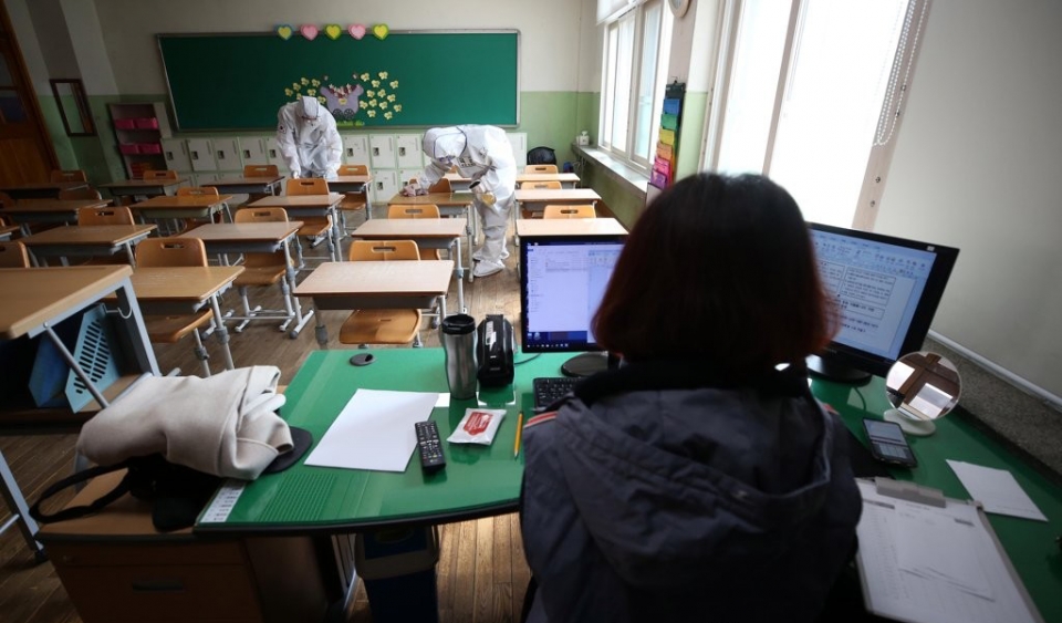육군 50사단 소속 장병들이 7일 대구시 중구 남산동 대구남산초등학교에서 신종 코로나바이러스 감염증(코로나19) 확산 방지를 위한 방역을 하는 가운데 아이들이 없는 빈 교실에서 한 선생님이 온라인 개학 준비를 하고 있다.
