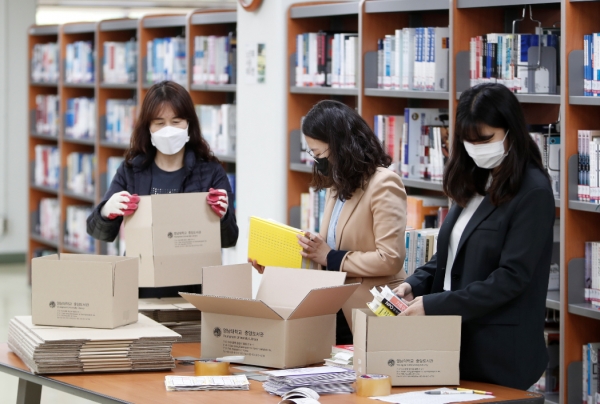 영남대 도서관 직원들이 학생들에게 배송할 책을 포장하고 있다.