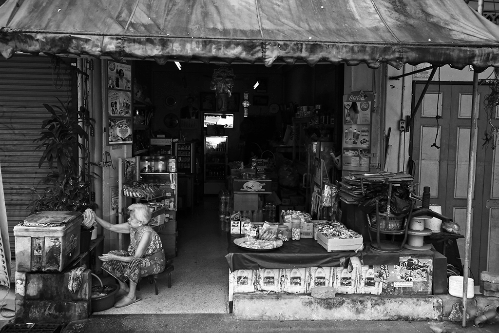 허름한 구멍가게에 앞에 앉아 손님을 기다리는 캄보디아의 할머니.
