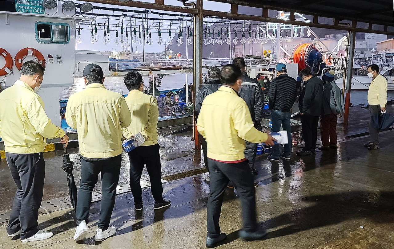 울릉군 해양수산과 직원들이 외지 어선 선원들에게 마스크를 전달하고 있다.