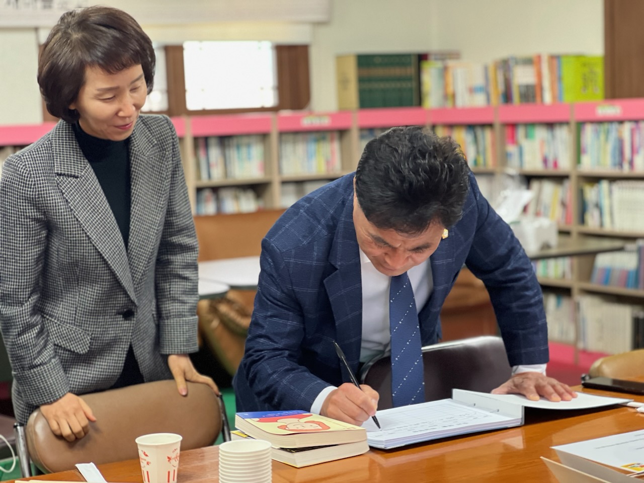 열려있는 무인책방에서 책을 빌리고 있는 김경숙 법전면장(왼쪽),김민호 봉화군의회 의원(오른쪽)